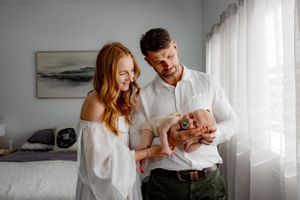 Modern nursery scene with a newborn being cradled by two loving parents.
