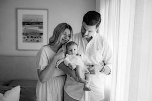 A black and white portrait of a family sharing a tender moment by a sunlit window.