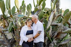 Couple poses together against a backdrop of large desert cacti and succulents.