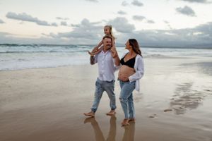 Family walking together along beach shoreline at sunset.