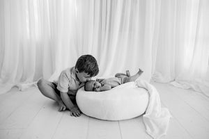 A series of black and white newborn photographs showing a sleeping baby in different poses on soft blankets.
