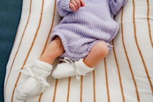 A pair of legs wearing cozy knit socks and a lavender sweater rests comfortably on a striped couch.