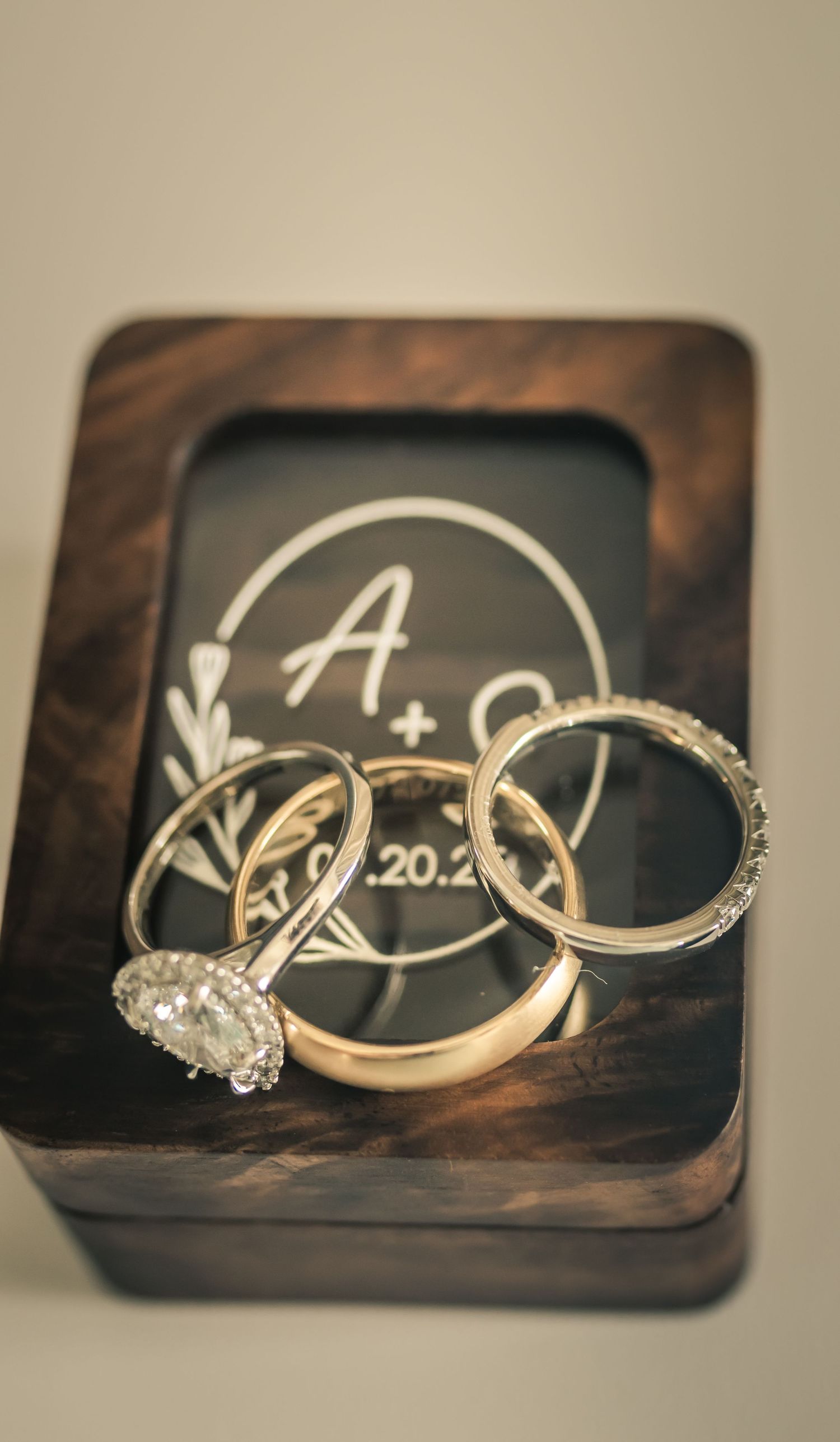 Wedding rings and bands displayed on a wooden box with monogram design.