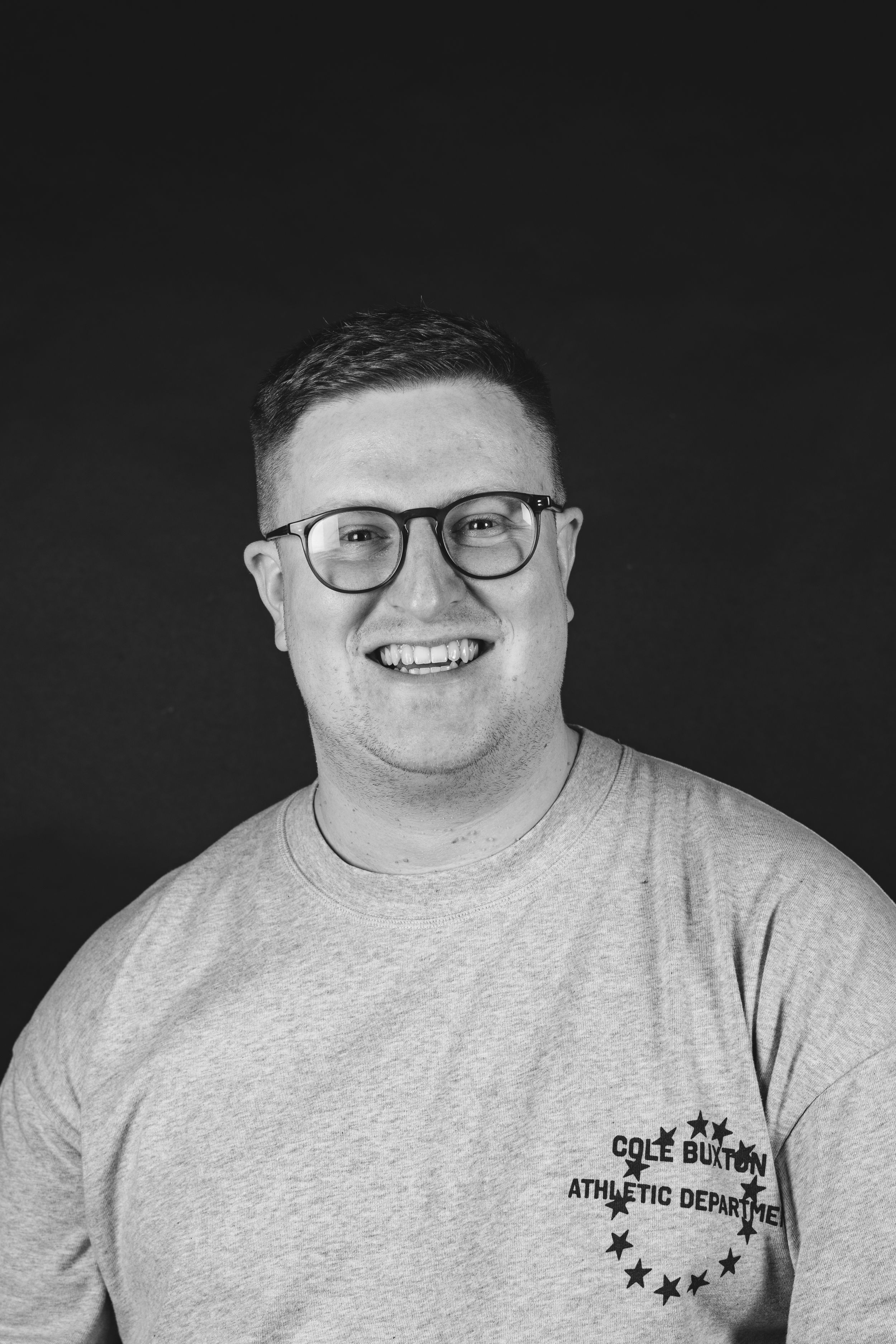 Portrait of person in white t-shirt against neutral background smiling warmly.