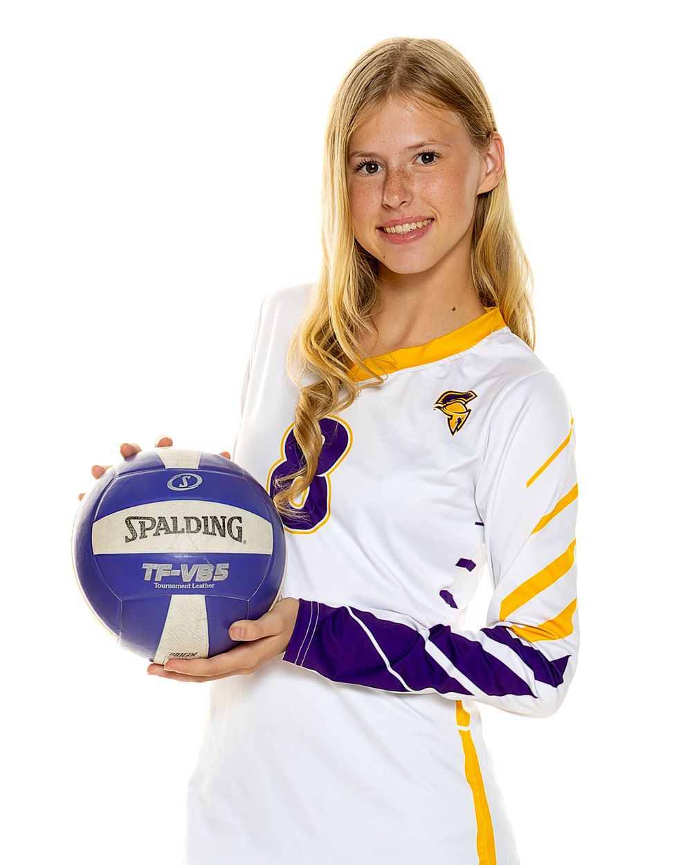 Volleyball player in white and purple uniform holds Spalding team volleyball.