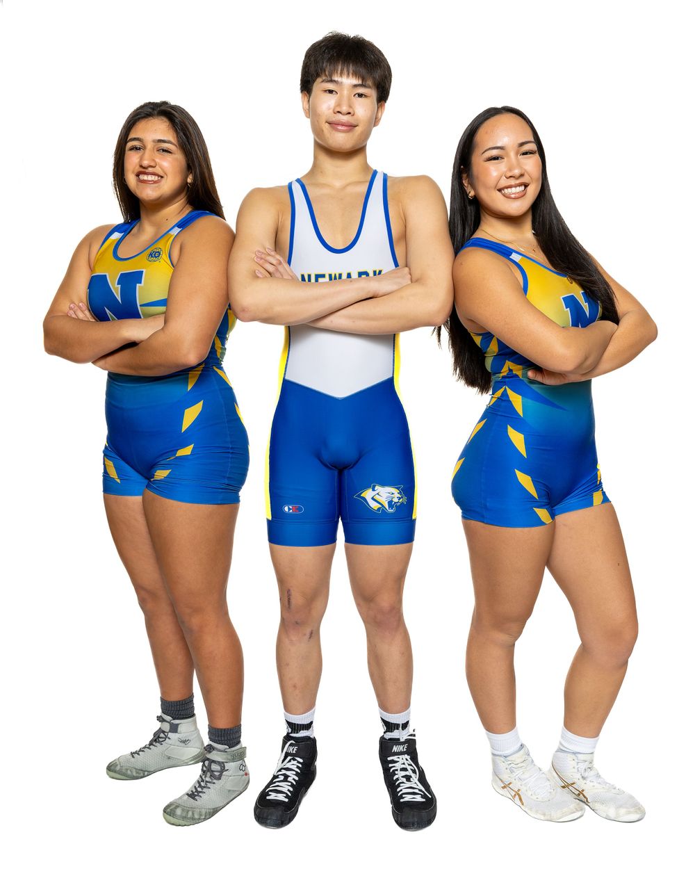 Three athletes pose together wearing matching blue and white wrestling uniforms.