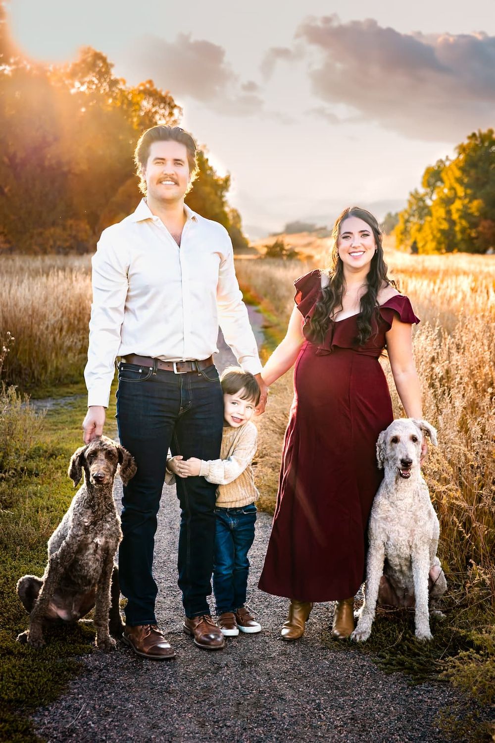 Outdoor family maternity photo with parents, child, and dogs at sunset by Denver maternity photographer.