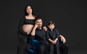A family dressed in black outfits poses together in a studio for stylish professional portraits.