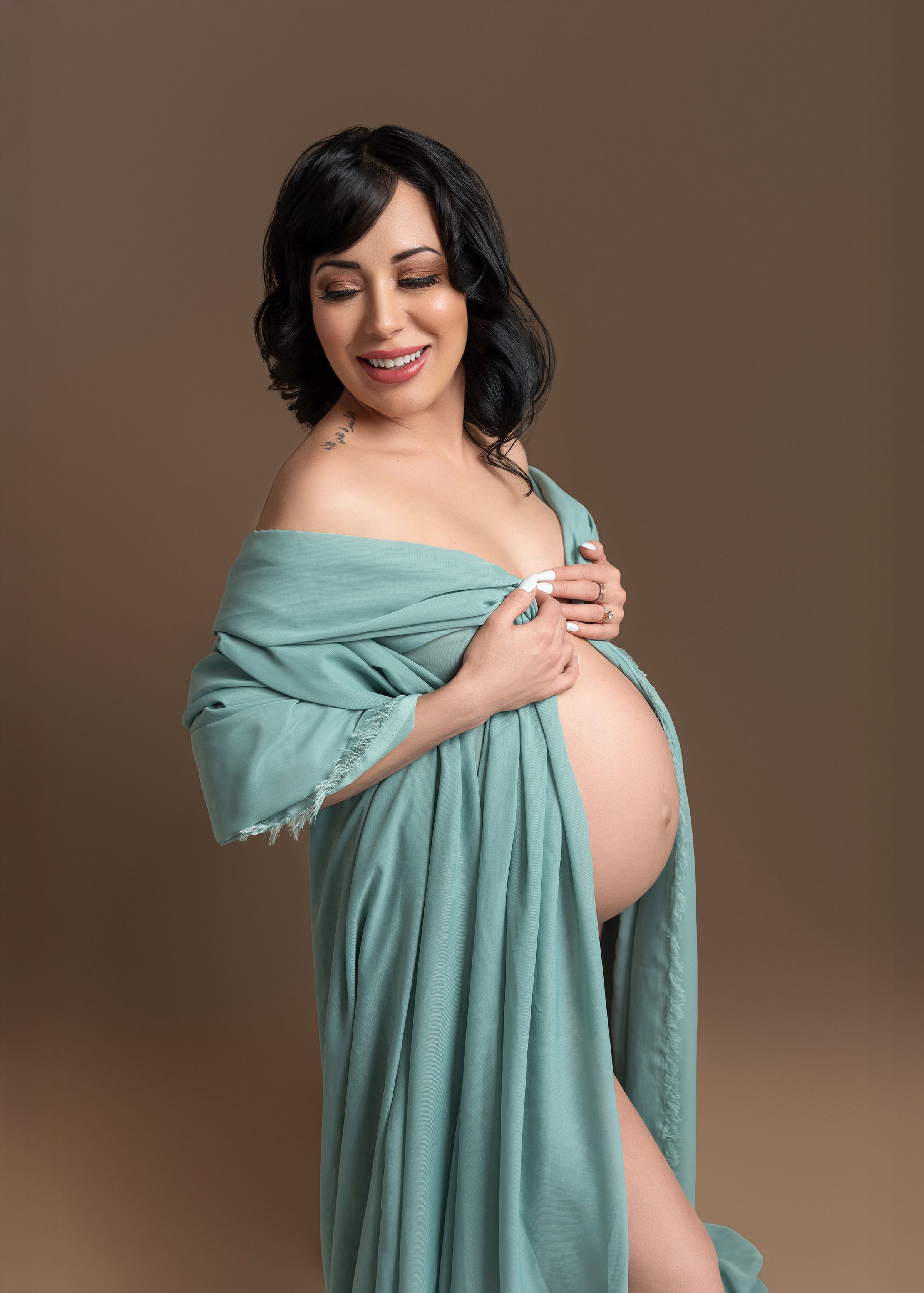 Tutorial showing step-by-step process of nursing wrap draping technique in soft mint green fabric against brown backdrop.