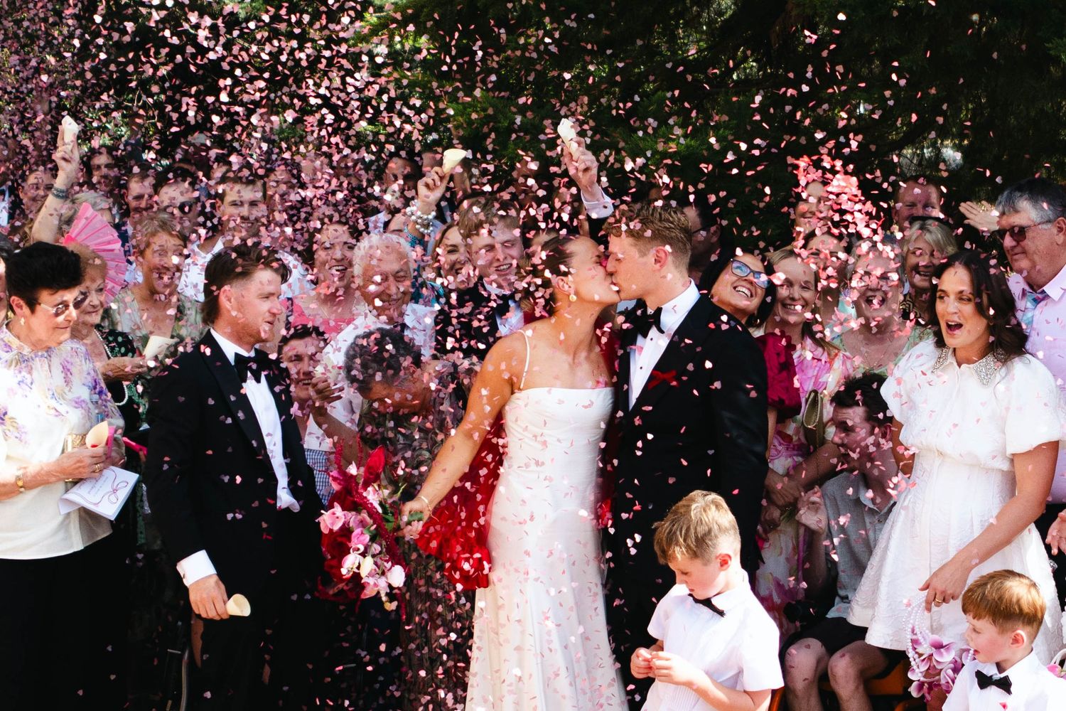Wedding celebration with pink flower petals being tossed in the air.