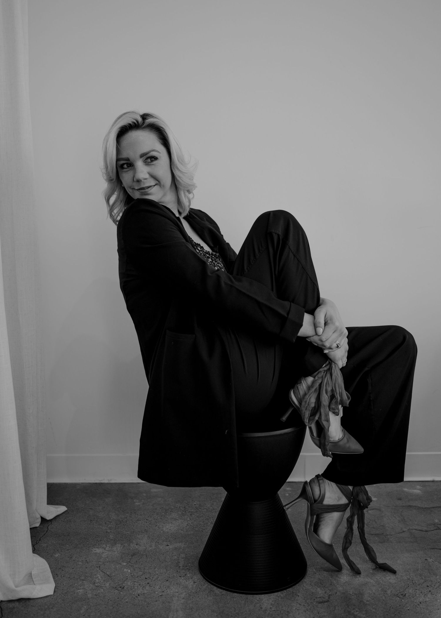 Dramatic black and white portrait showing elegant pose on modern chair.