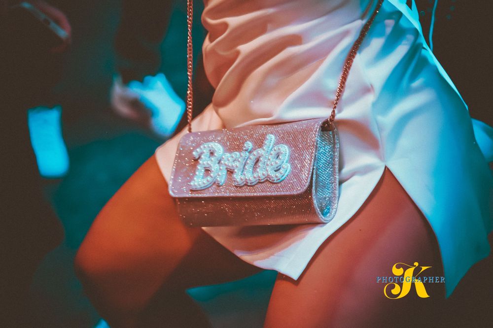 Pink glittery purse with the word 'Bride' in sparkly text photographed with dramatic blue lighting.