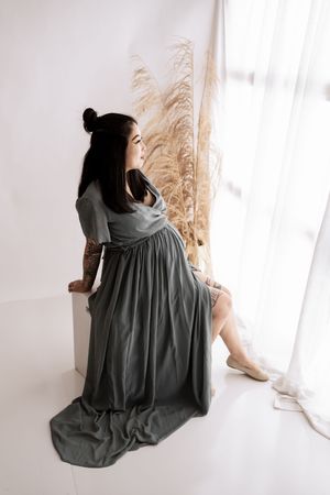 A sequence of minimalist photographs featuring someone in a dark gray dress posed elegantly in a bright white studio setting.