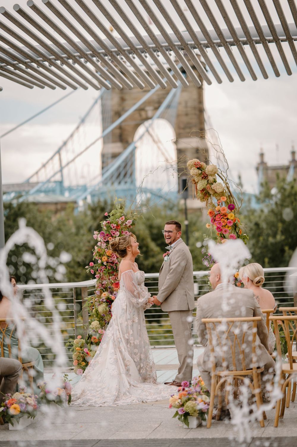 Elegant outdoor wedding ceremony setup with lush floral arrangements and modern white architectural details in background.