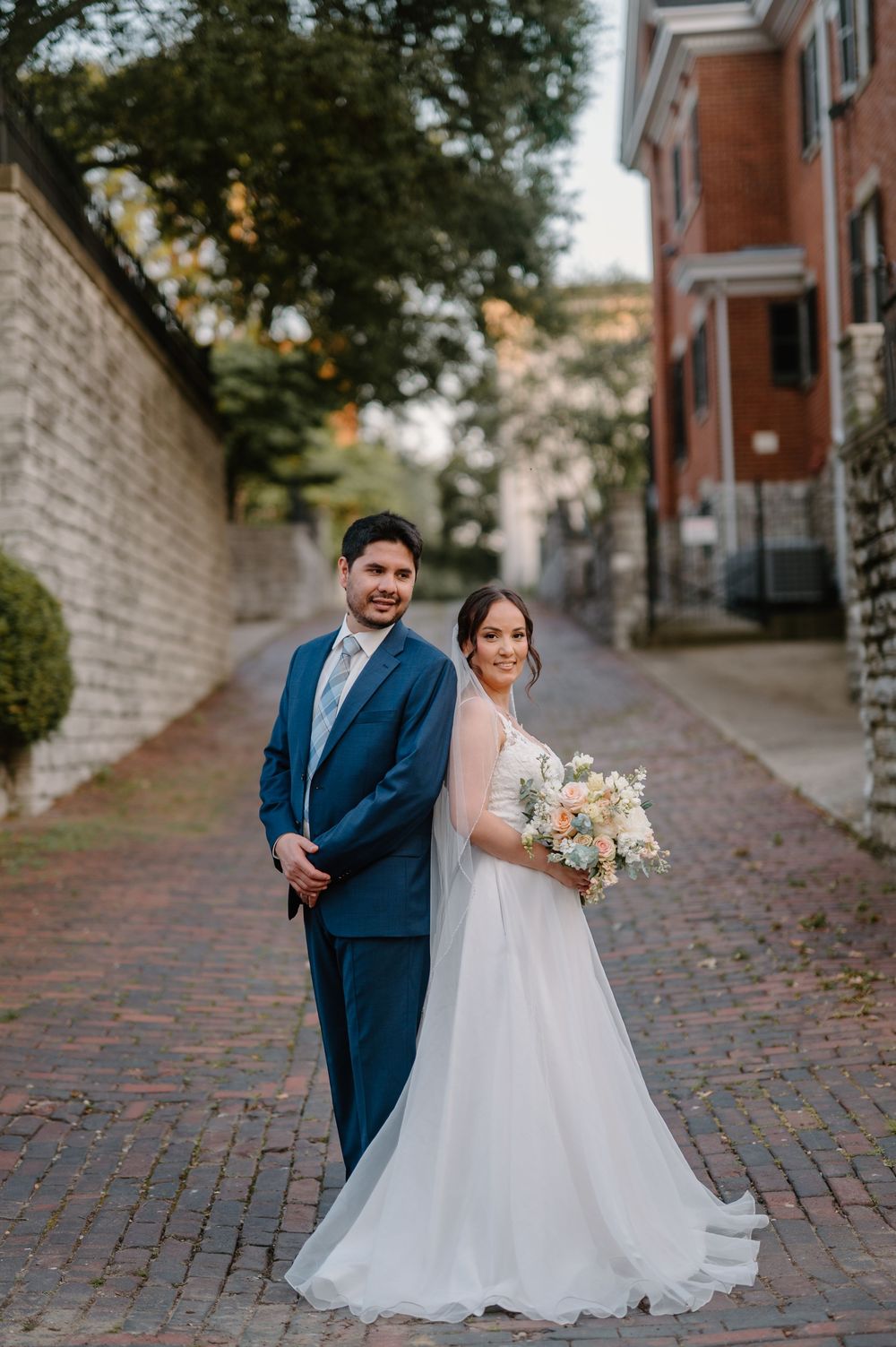 A charming cobblestone path surrounded by historic buildings serves as a scenic wedding photo location.