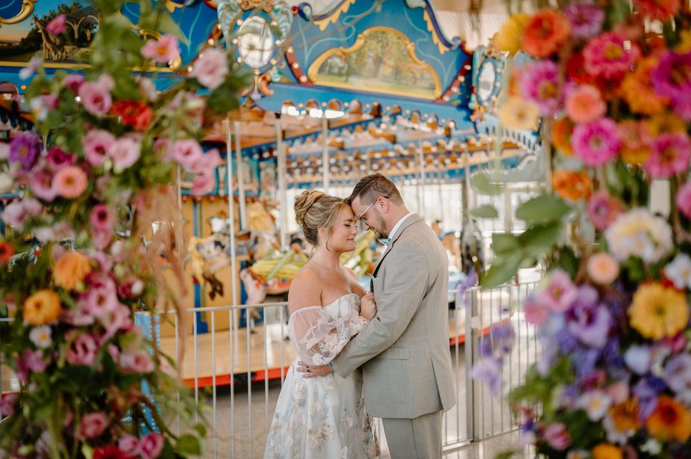 Romantic carousel photoshoot with floral decorations and whimsical carnival backdrop at an amusement park.