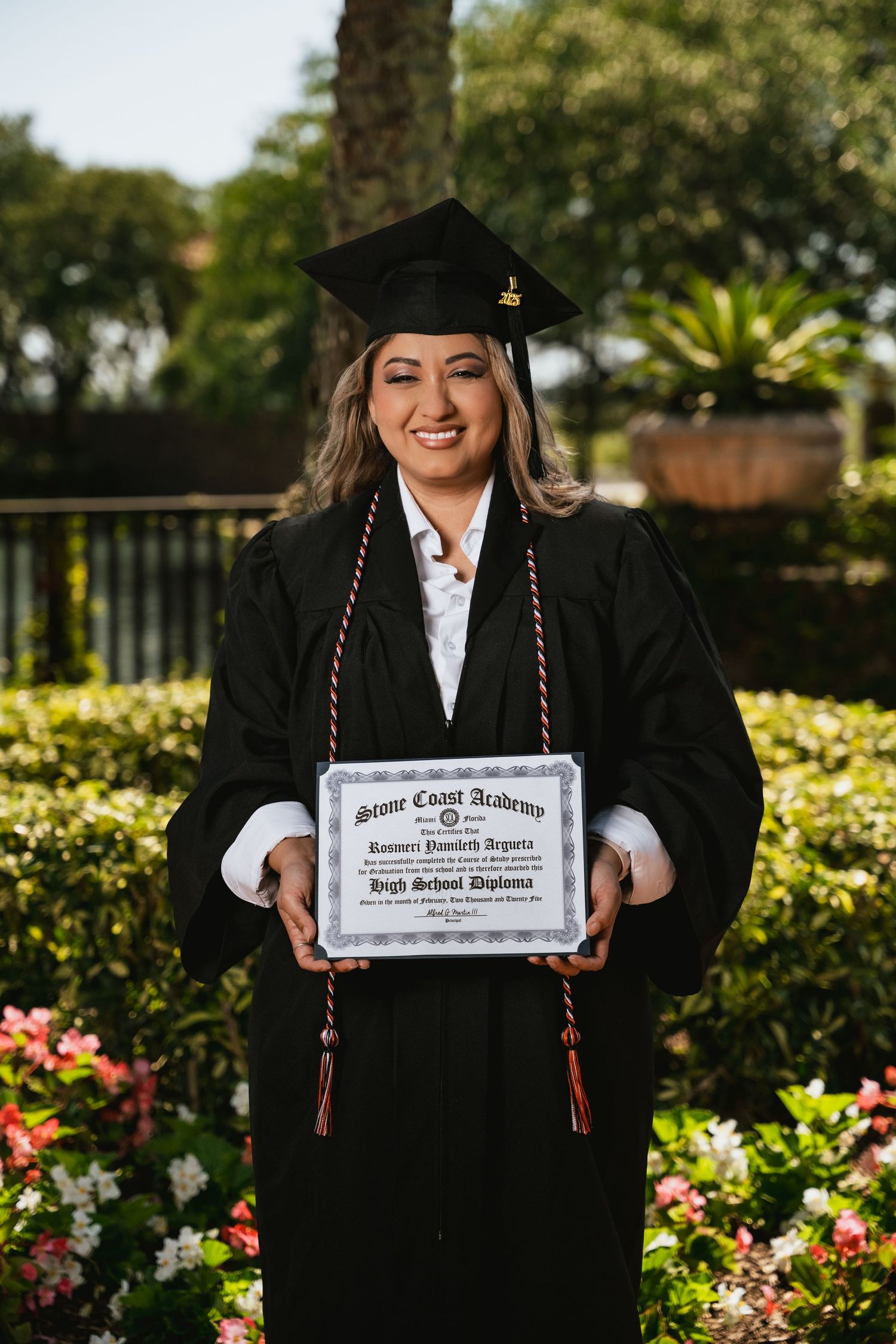 Graduation photos with a diploma in a beautiful garden setting with blooming roses and greenery.