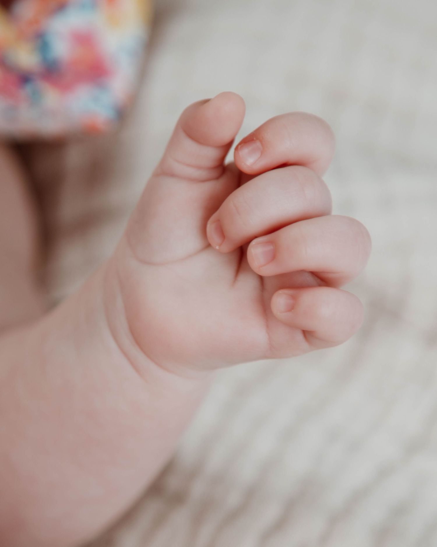 Close-up of tiny baby feet resting on colorful floral patterned fabric.