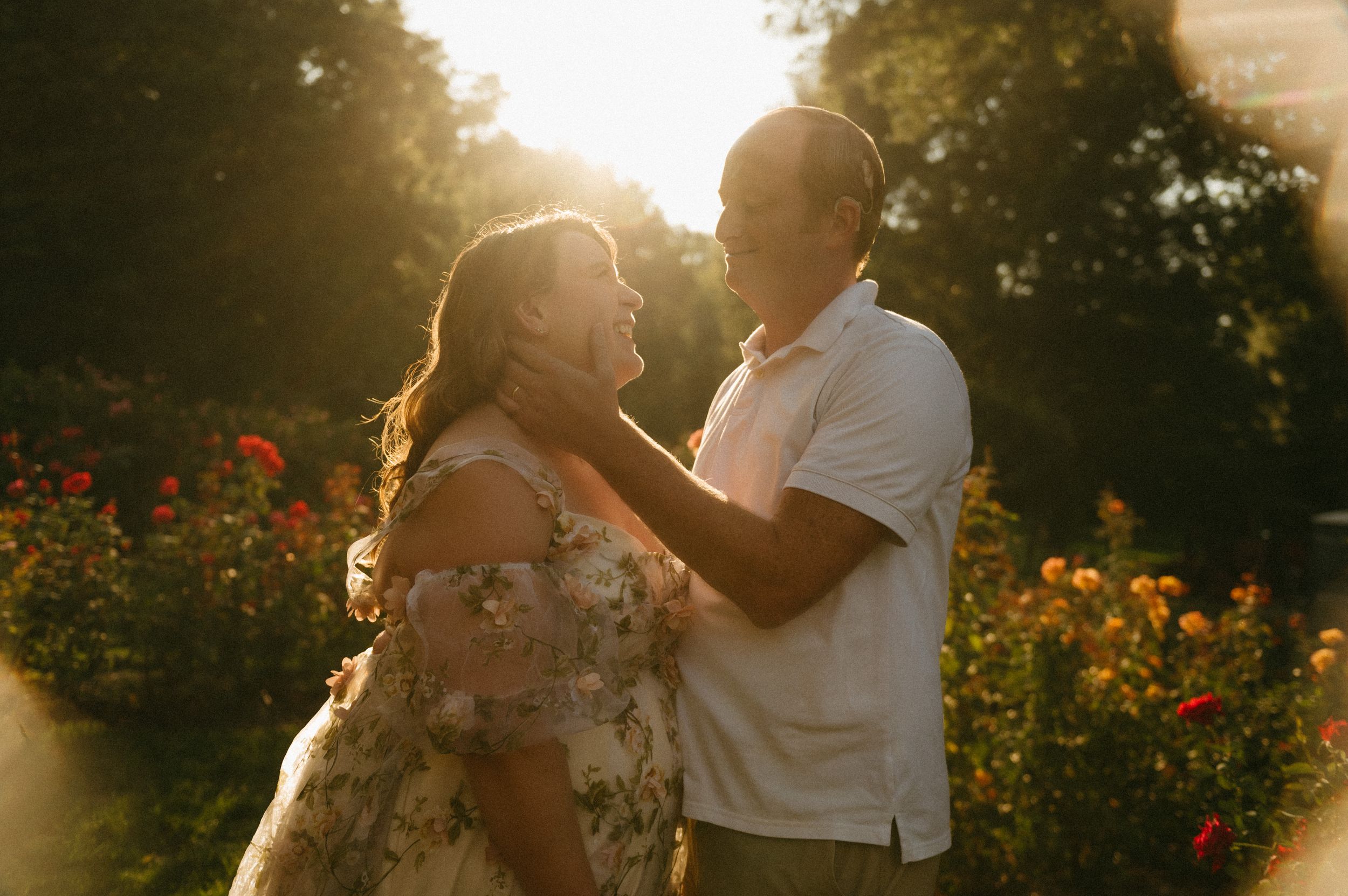 Couple sharing a romantic moment in a sunlit garden with colorful flowers blooming in the golden hour light.