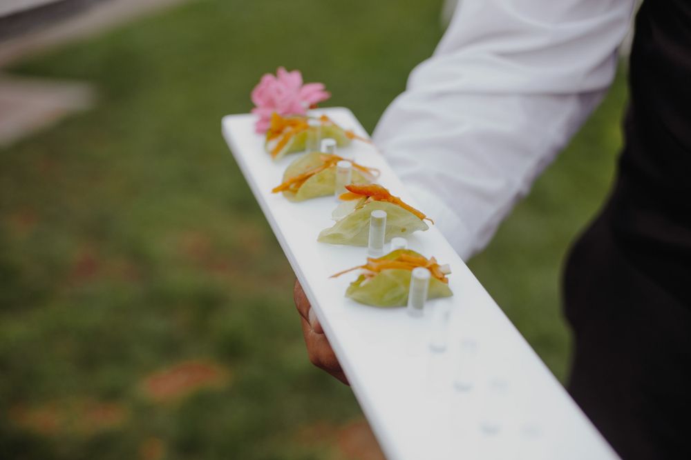 Colorful appetizers with flowers arranged in a line on a white surface.