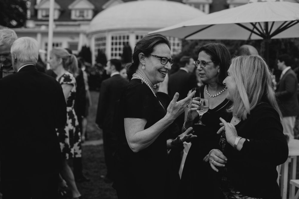 Black and white photo of guests mingling at an outdoor cocktail reception.