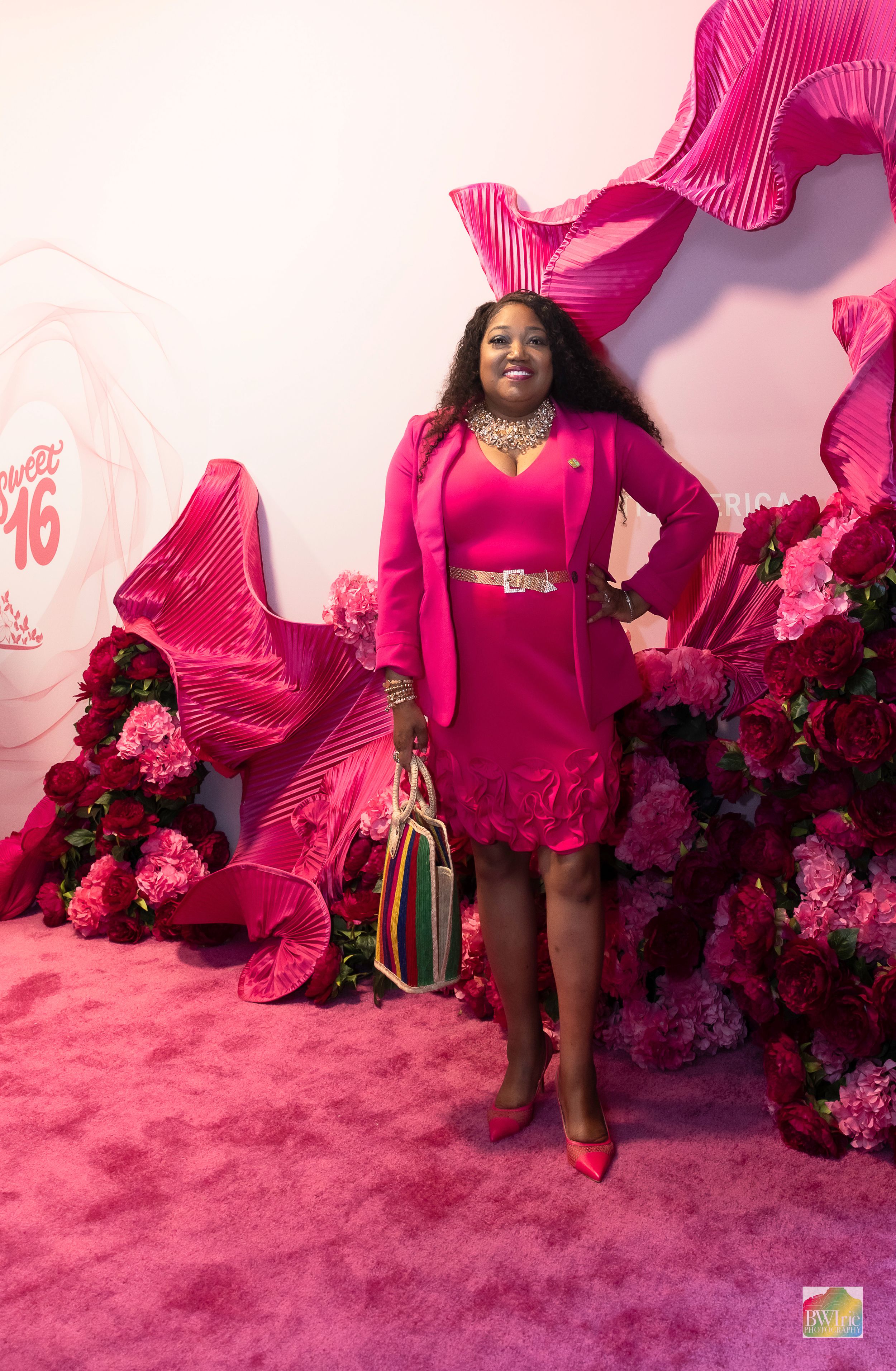 Vibrant pink fashion display with floral decorations and dramatic fabric installations.