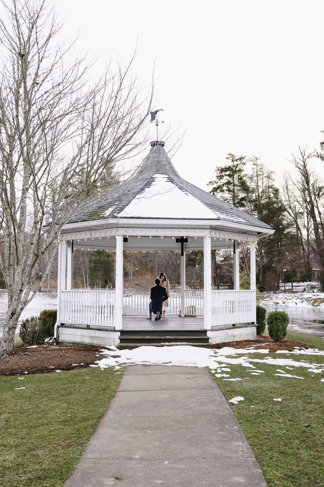 Snow-dusted white gazebos connected by walkways in a winter garden setting. Château des  Fleures Wedding Photographer