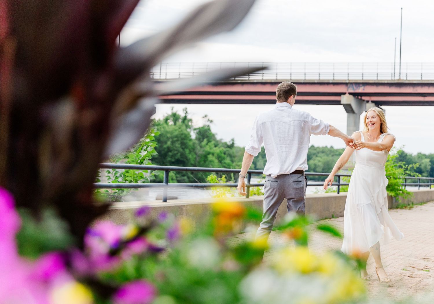 A dancing couple twirls on a terrace with colorful flowers in the foreground.