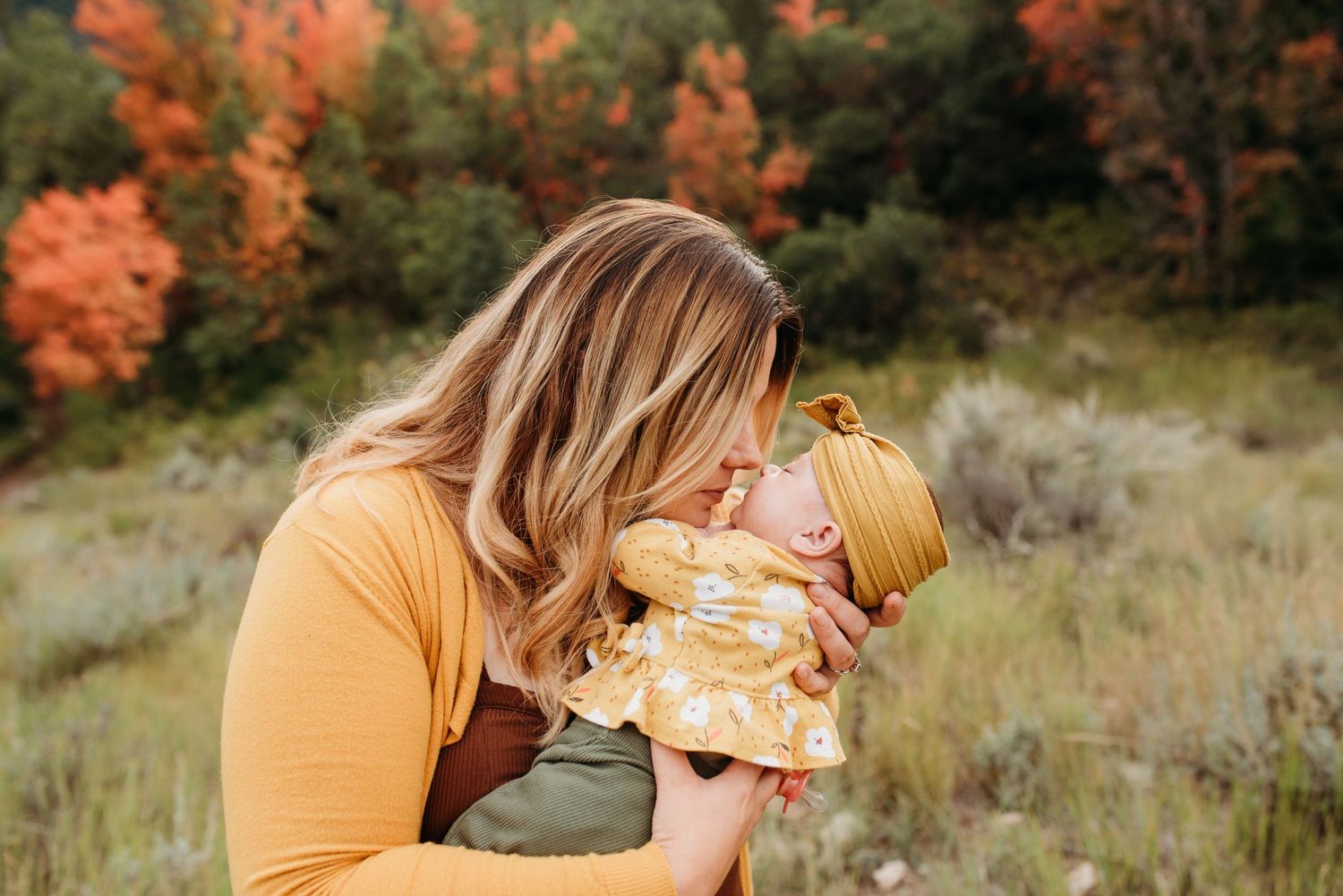 Sweet autumn outdoor portrait in a field with vibrant orange foliage in the background.