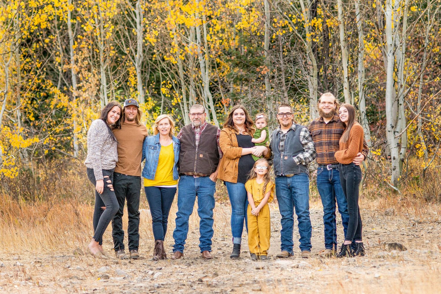 Group portrait in casual attire against autumn aspen trees with golden leaves in the background.