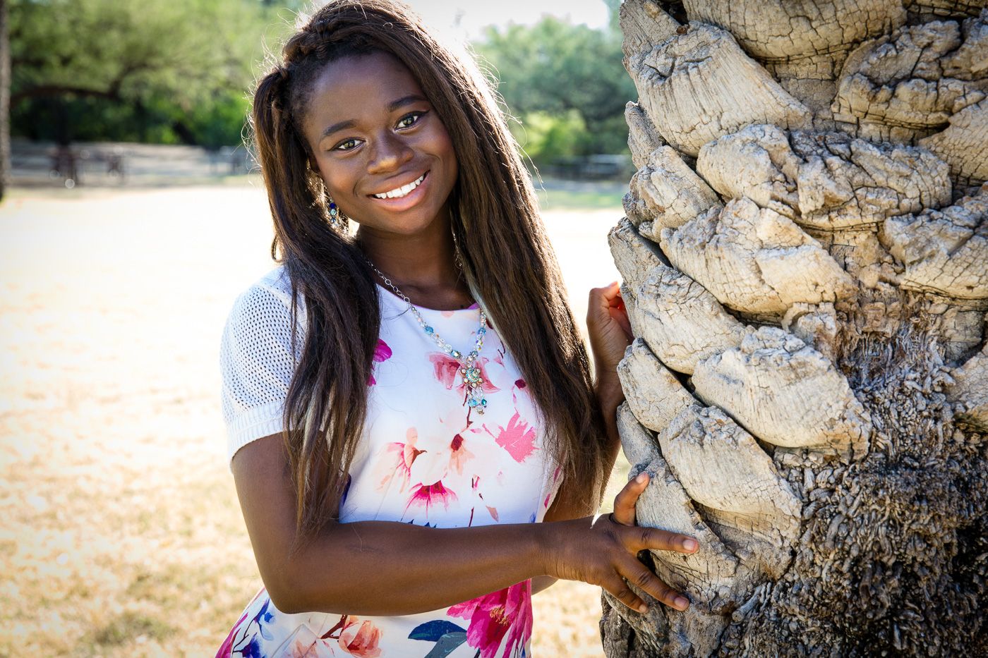 Black African American Girl in a flowery dress leaning next to a palm tree