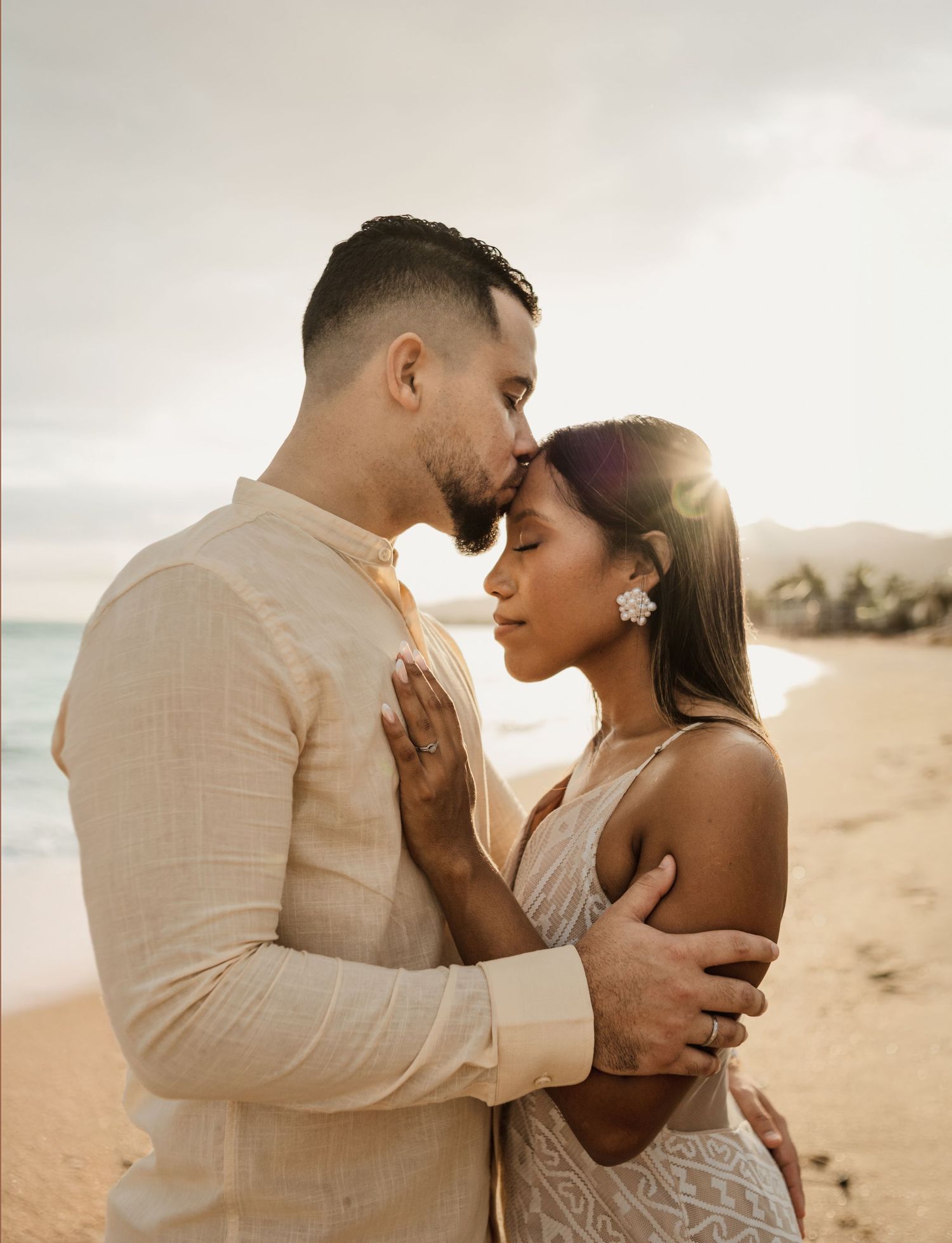 Intimate beachside moment between couple in neutral tones during golden hour.