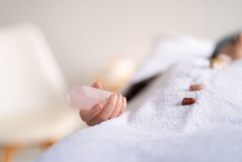 Crystal held during relaxation therapy session with white towel background.