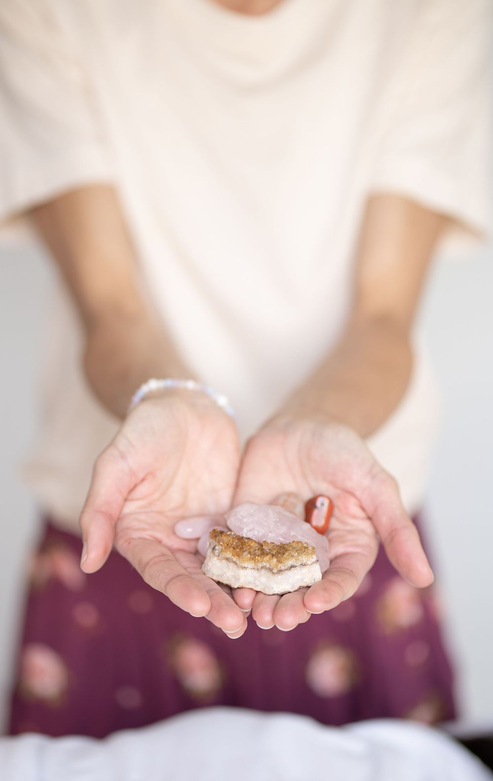 Hands holding a small decorative macaron cookie while wearing purple patterned pants.