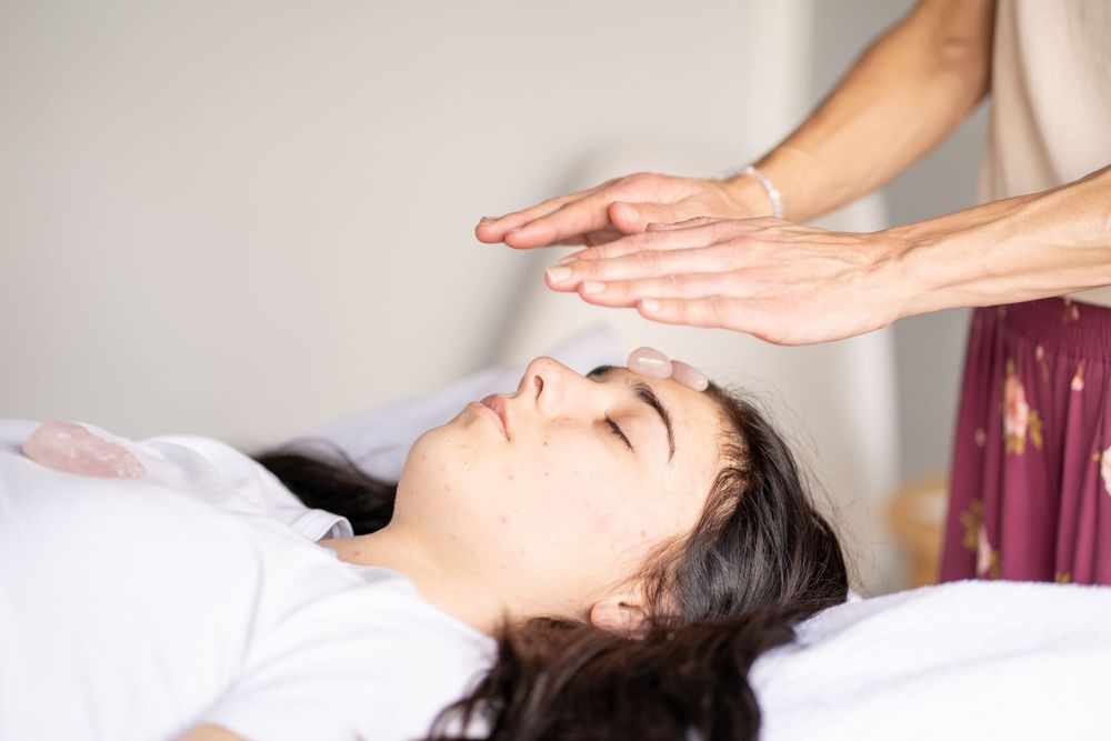 Energy healing hands hovering over person during relaxation treatment.