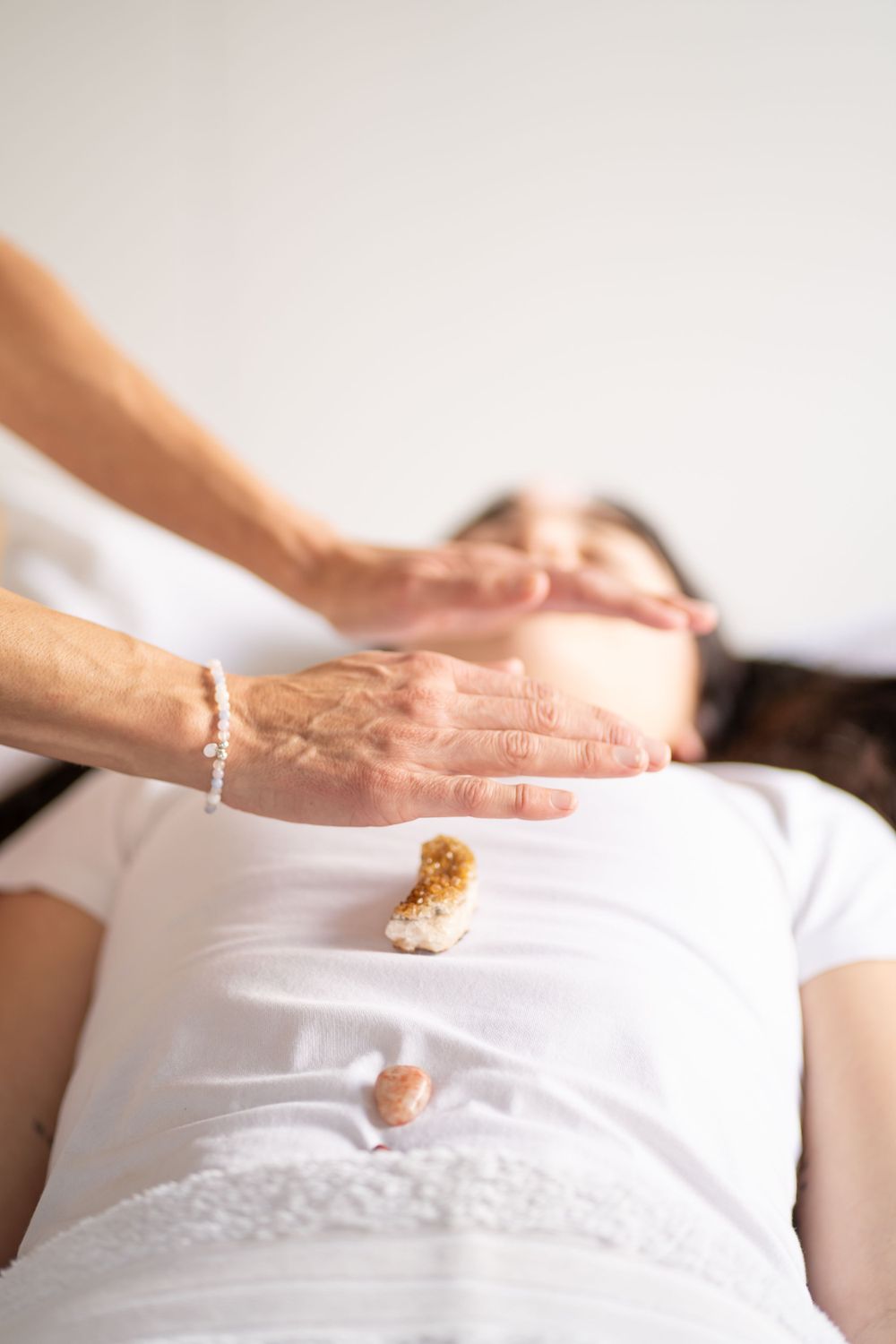 Healing session with crystals being placed on person wearing white clothing.