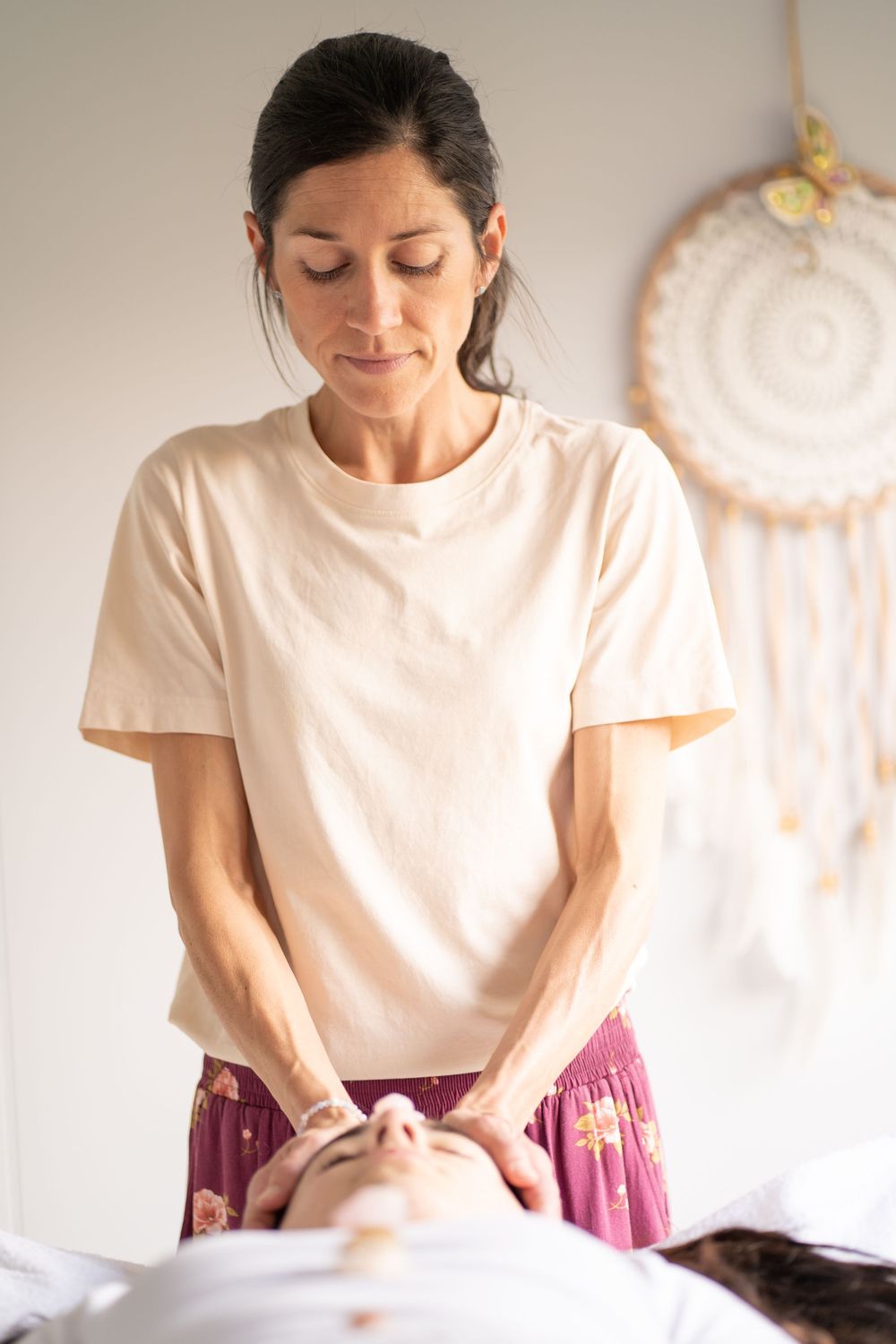 Wellness practitioner performing energy healing treatment in serene setting.