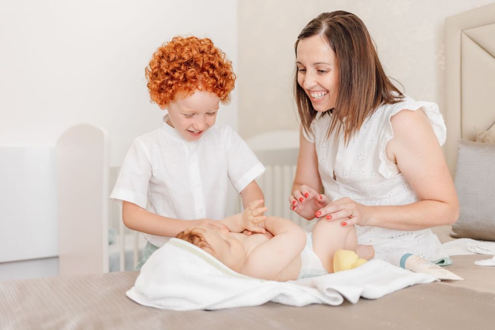 Two people changing a baby on a changing table with care supplies.
