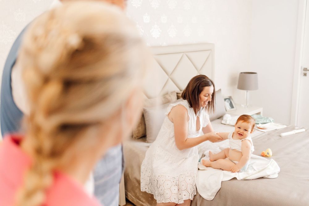 Family gathered on bed during morning routine with baby.