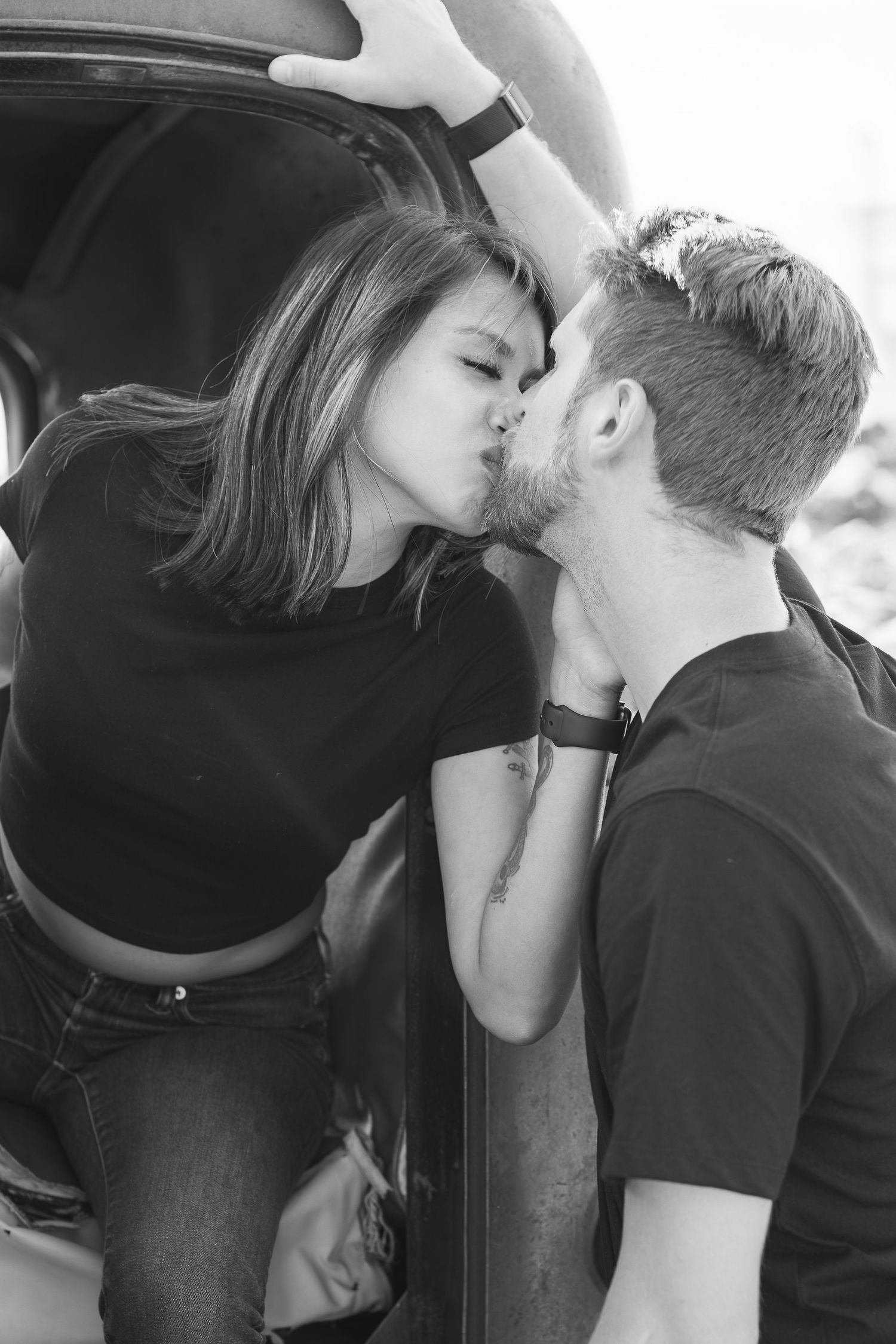 A black and white photo series showing two people kissing in a car.