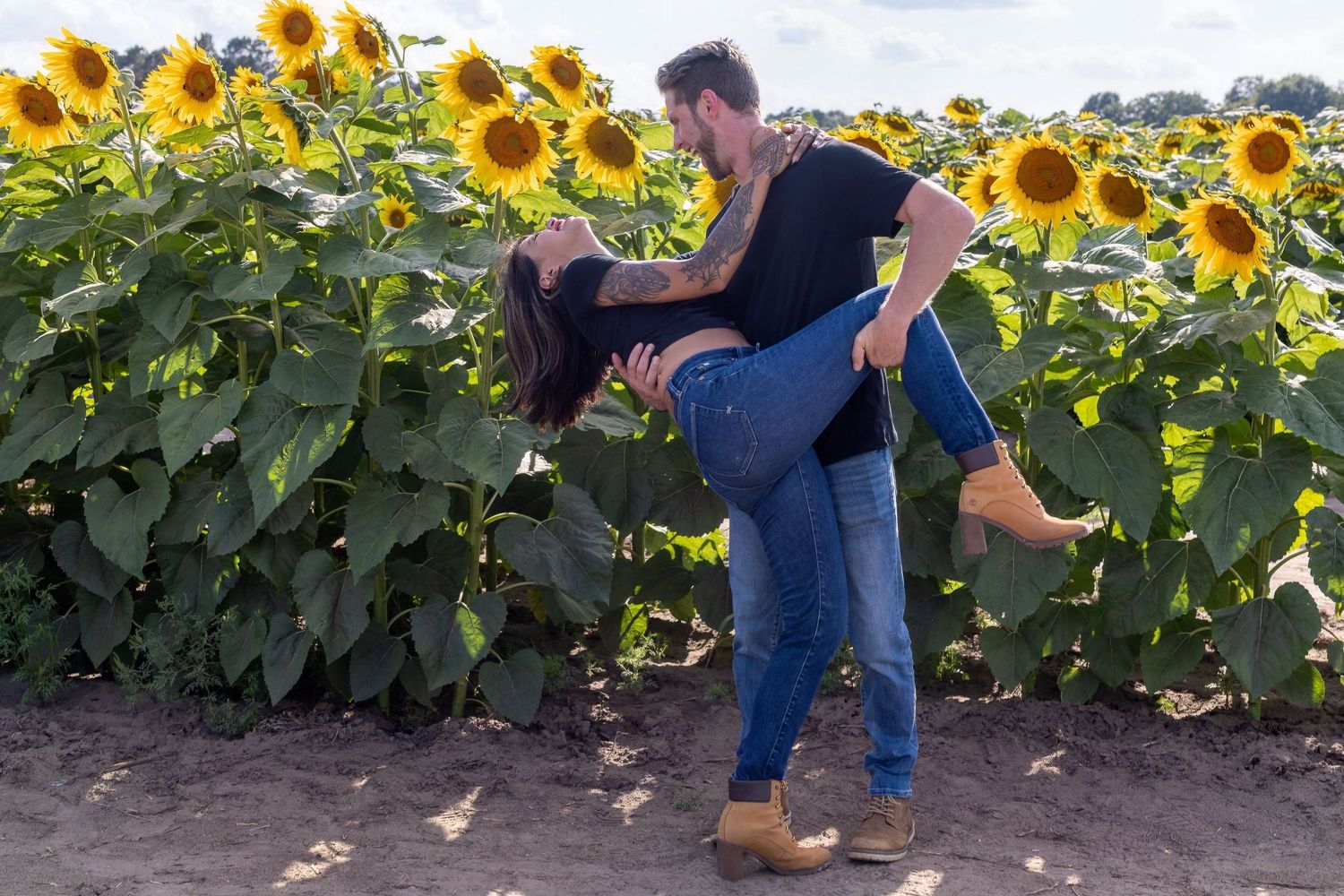 A romantic moment unfolds next to a sunflower field as a couple shares a passionate kiss at sunset.