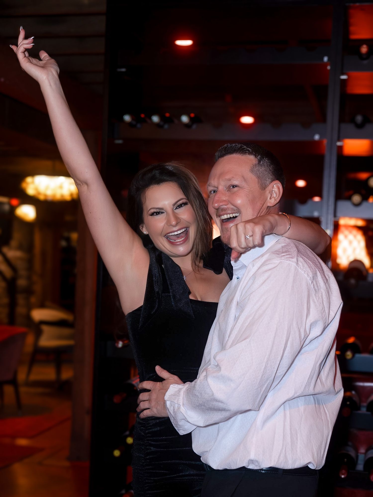A couple performs an energetic dance move in a restaurant or bar setting.