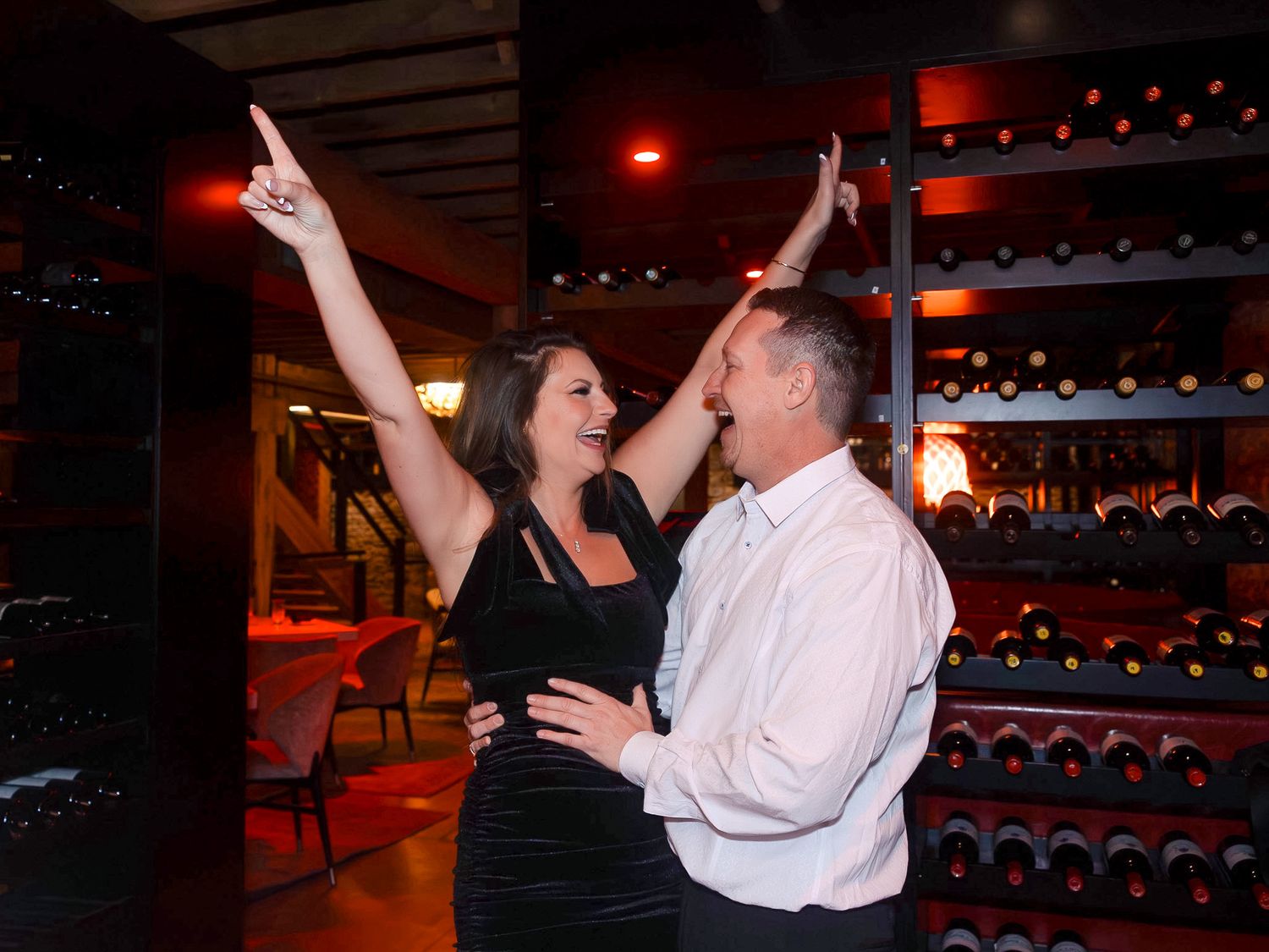A couple sharing a special moment during a proposal in a dark venue with red ambient lighting.