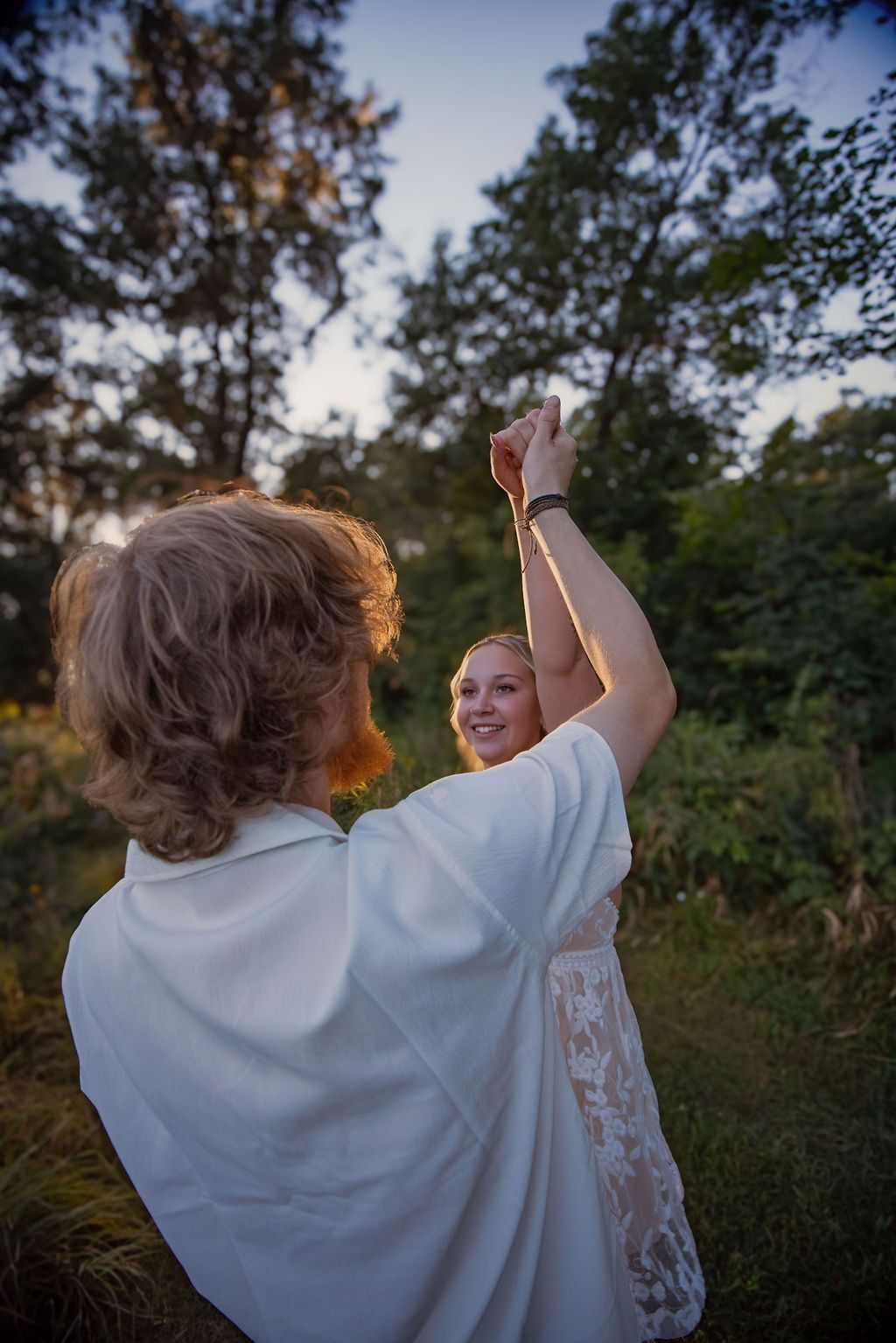 Happy couple dancing together outdoors during golden hour.