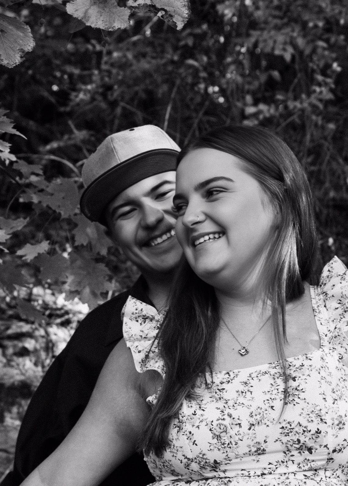 Black and white intimate portrait of a happy couple among leafy foliage.