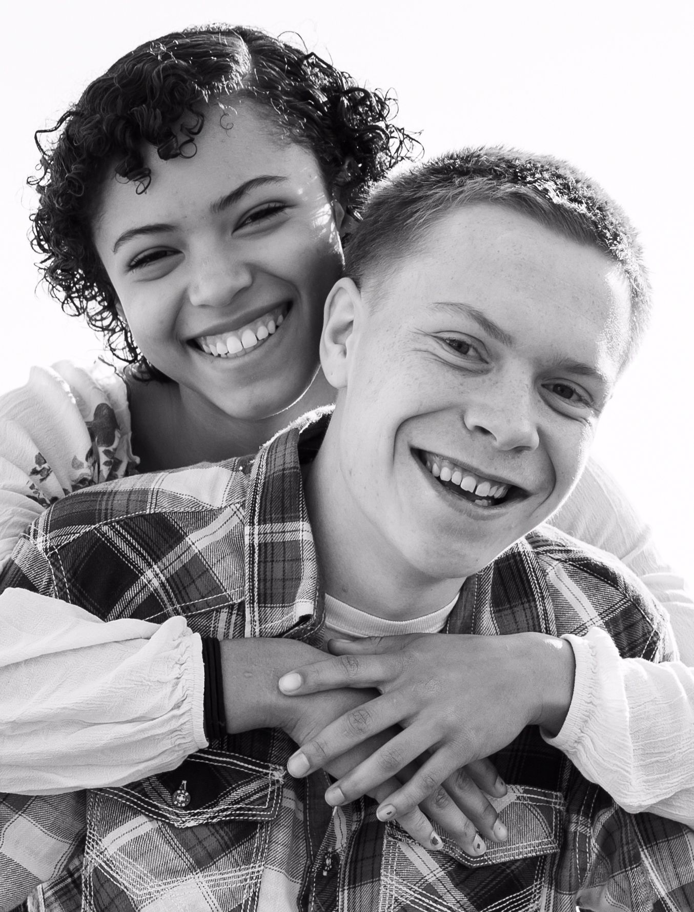 A black and white portrait of a couple sharing an intimate embrace and genuine smiles.