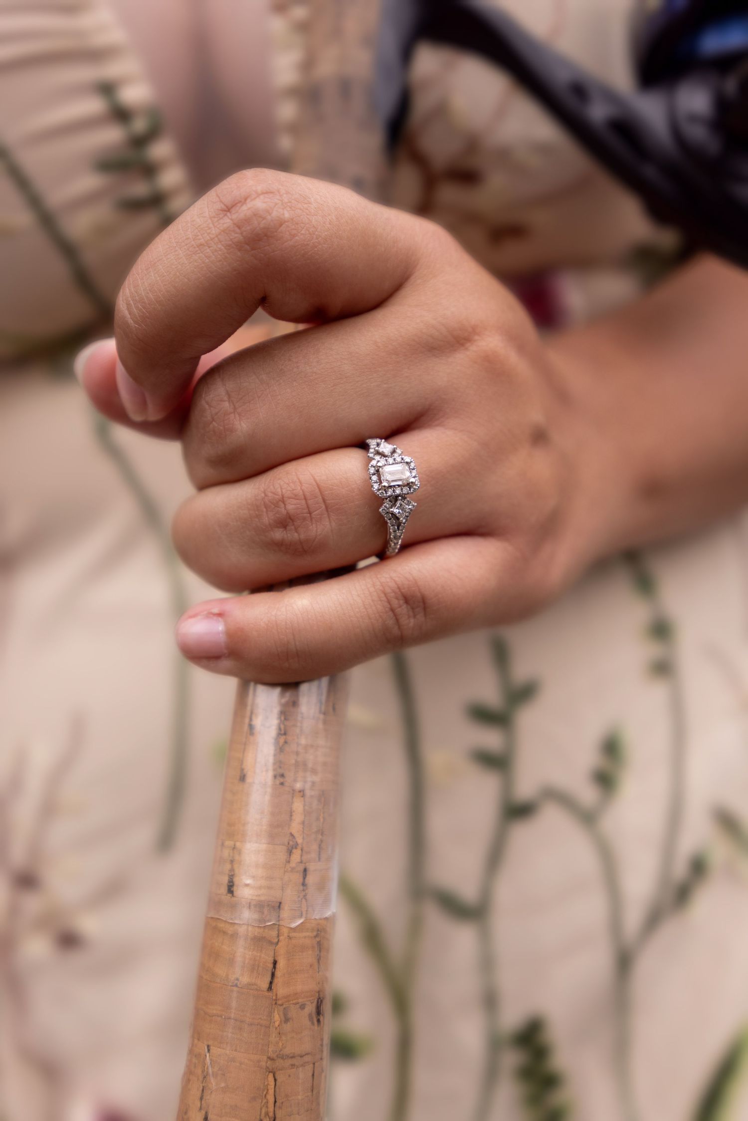 Close-up view of a sparkling diamond engagement ring on a finger against a blurred natural background.