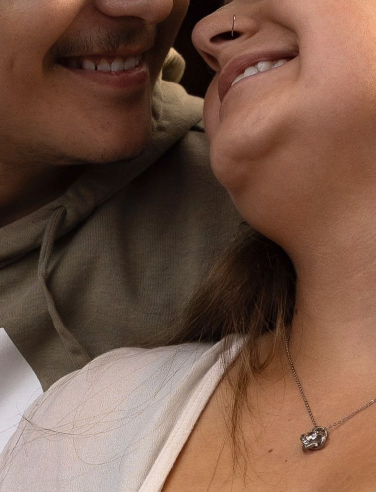 Close-up capture of genuine smiles and delicate necklace details.