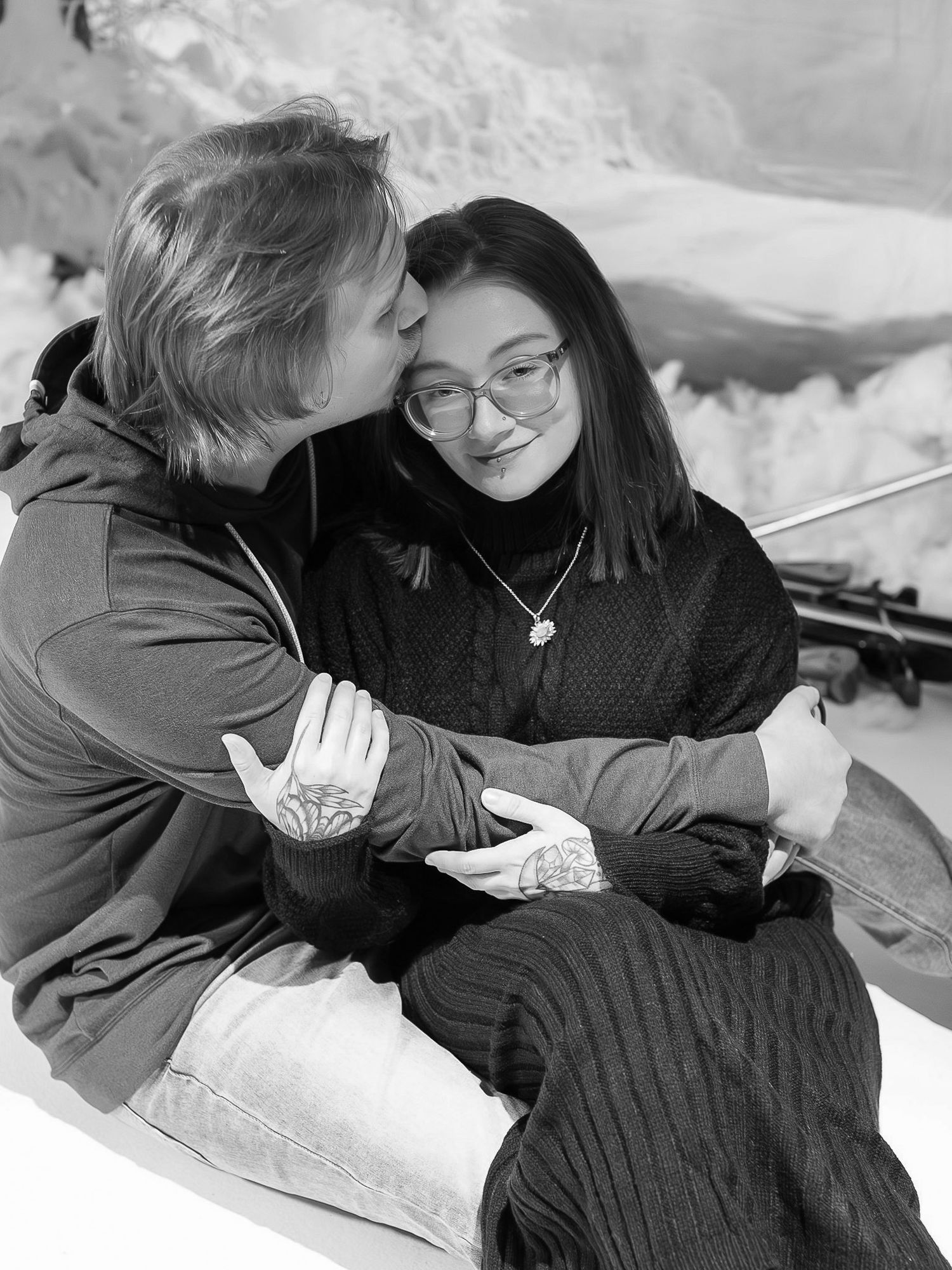 Four black and white photos showing two people embracing and sharing an intimate moment in the snow.
