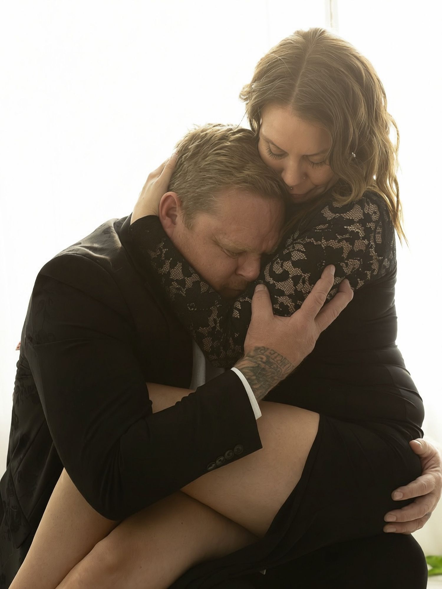 A couple in black clothing embraces emotionally in a series of intimate portrait photographs.